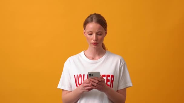 Geconcentreerde Vrouw Vrijwilliger Typen Wijzen Naar Telefoon Oranje Studio — Stockvideo