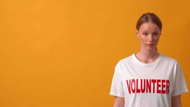 Geconcentreerde Vrouw Vrijwilliger Kijken Naar Camera Oranje Studio — Stockvideo