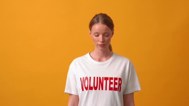 Serieuze Vrouw Vrijwilliger Opening Ogen Bij Camera Oranje Studio — Stockvideo