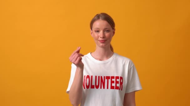 正の女性ボランティアショー韓国のハート形ジェスチャーでカメラでザオレンジ色のスタジオ — ストック動画