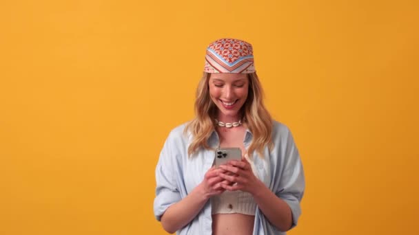 Gülümseyen Sarışın Kadın Turuncu Stüdyoda Telefonla Mesajlaşıyor — Stok video