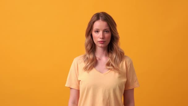 Geconcentreerde Blonde Vrouw Geel Shirt Kijkend Naar Camera Oranje Studio — Stockvideo