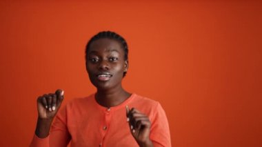 Turuncu stüdyoda dans eden komik Afrikalı kadın.