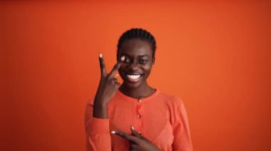 Gülümseyen Afrikalı kadın turuncu stüdyoda oynaşıyor.