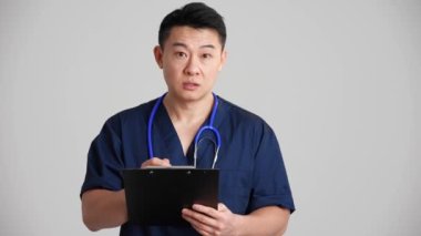 Konsantre Asyalı doktor gri stüdyoda anestezi topluyor.