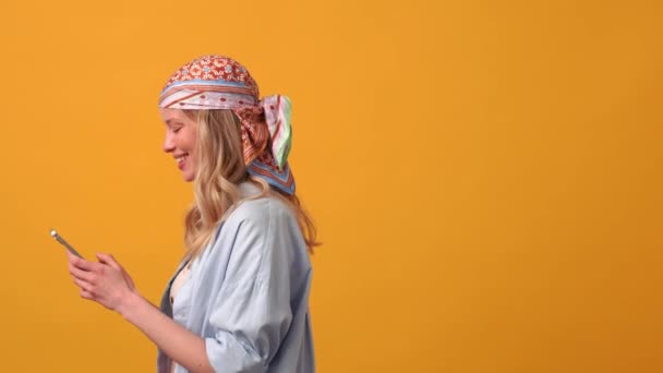 Turuncu Stüdyoda Telefonla Mesajlaşan Pozitif Sarışın Kadın — Stok video