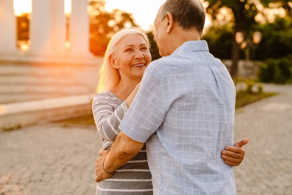 Biała Para Seniorów Przytula Się Uśmiecha Świeżym Powietrzu Zachodzie Słońca — Zdjęcie stockowe