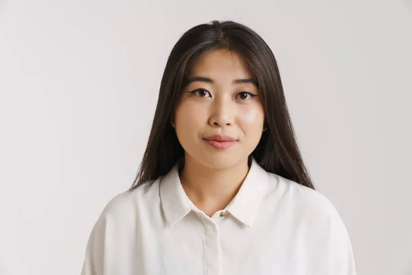 年轻的亚洲女人穿着衬衫 摆出一副姿势 看着隔着白墙的相机 — 图库照片