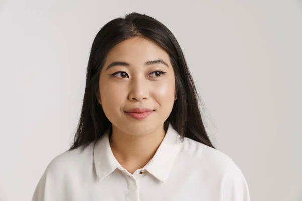 年轻的亚洲女人穿着衬衫 面带微笑 隔着白墙望着旁边 — 图库照片