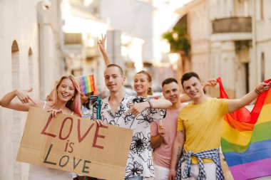 Bir grup gülen insan, lgbt topluluğunun geçit töreninde sokakta yürüyor.