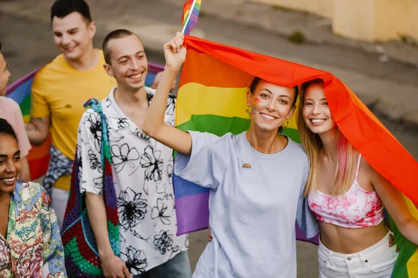 若いレズビアンカップル歩くとともに虹旗中にプライドパレードで街の通り — ストック写真