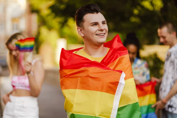 Zbliżenie Uśmiechniętego Młodzieńca Tęczową Flagą Stojącego Wśród Grupy Uśmiechniętych Ludzi — Zdjęcie stockowe