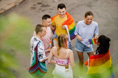 Şehir caddesindeki geçit töreninde gülümseyen ve konuşan çok ırklı erkek ve kadınlar.