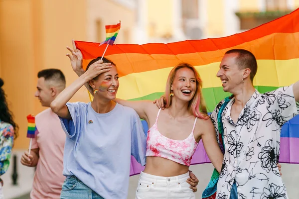 都市の通りでプライドパレード中に虹の旗で歩く多人種間の男性と女性 — ストック写真