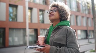 Yeşil kapüşonlu yakışıklı Afrikalı kadın etrafa bakıyor ve dışarı çıkıyor.