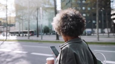 Dışarıda yürürken telefonla mesajlaşan Afrikalı kadının arka plan görüntüsü