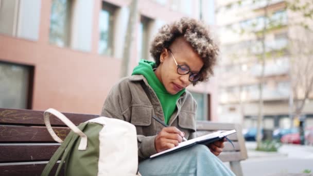 Confident African Woman Wearing Green Hoodie Writing Notes Notepad Outdoors — Stock Video