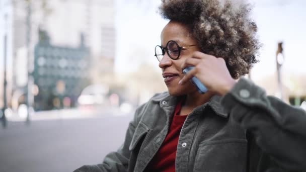 Uśmiechnięta Dorosła Afrykanka Ubrana Luźne Ubrania Rozmawiająca Przez Telefon Siedząca — Wideo stockowe
