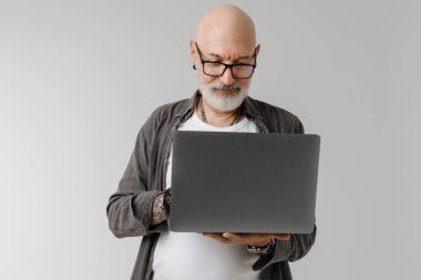 Gözlüklü kel bir Avrupalı dizüstü bilgisayarla çalışıyor. Beyaz arka planda izole edilmiş.