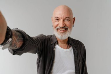Beyaz arka planda izole edilmiş selfie çekerken sakallı kel Avrupalı adam gülümsüyor.