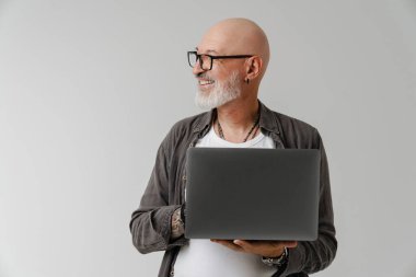 Beyaz arka planda laptopla çalışırken gülümseyen kel Avrupalı adam