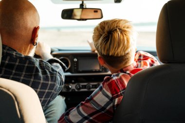 Orta yaşlı mutlu bir baba ve anaokulu çocuğu bir arabada oturuyor.