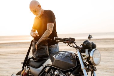 Yaz günü motosikletle dışarıda poz veren cesur bir son sınıf öğrencisi.