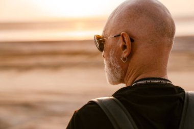 Güneş gözlüğü takan cesur bir adam yaz günü dışarı bakıyor.