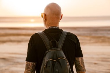 Sırt çantalı cesur adam yaz günü dışarı bakıyor.