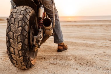 Motosiklet üzerinde dövmesi olan siyah tişört giyen olgun bir adam.