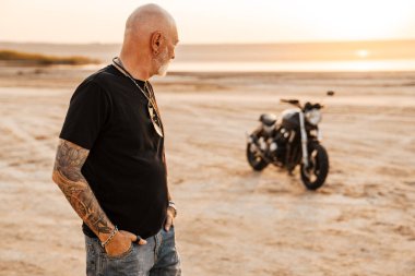 Yaz günü motosikletle dışarıda poz veren cesur bir son sınıf öğrencisi.