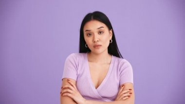 Mor tişört giyen Asyalı esmer kadın mor stüdyoda vıdı vıdı jest yapıyor.