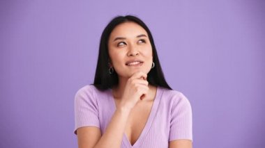 Mor tişört giyen Asyalı düşünceli esmer kadın mor stüdyoda düşünüyor.