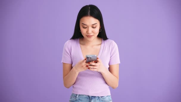 Frumos Asiatic Bruneta Femeie Purtând Tricou Violet Texting Mobil Studioul — Videoclip de stoc