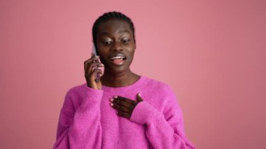 Pembe stüdyoda telefonla konuşan yakışıklı Afrikalı kadın.