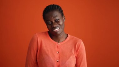 Tatminsiz Afrikalı kadın turuncu stüdyoda kameraya el sürüyor.