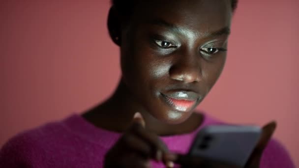 Smiling African Woman Texting Phone Pink Studio — Stock Video