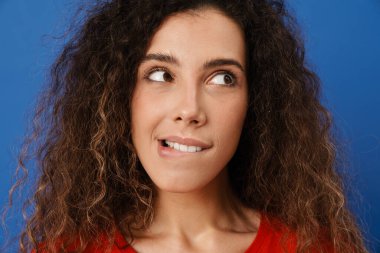 Genç esmer kadın dudağını ısırıyor ve mavi duvarın üzerinden tek başına bakıyor.