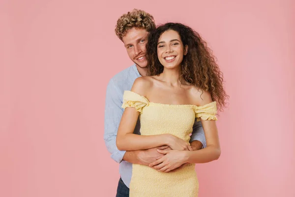 若いですホワイトカップル抱擁と笑顔でカメラで一緒に隔離されたピンクの壁 — ストック写真