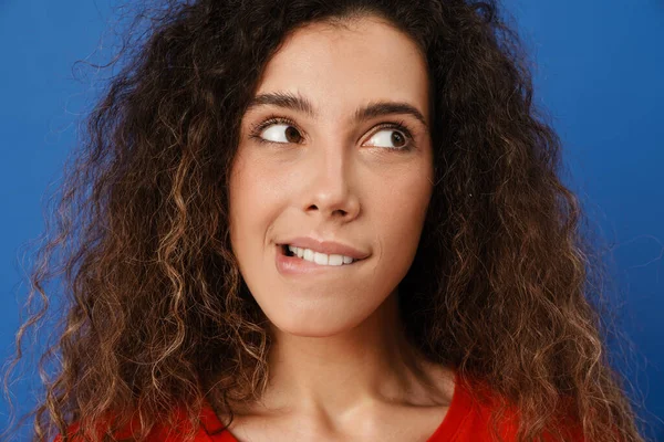 Genç esmer kadın dudağını ısırıyor ve mavi duvarın üzerinden tek başına bakıyor.