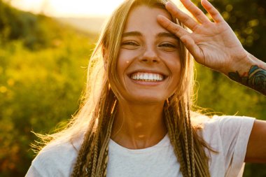 At kuyruklu beyaz bir kadın dışarıda kameraya bakıp gülüyor.