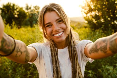 Dışarıda selfie çekerken gülümseyen genç bir kadın.