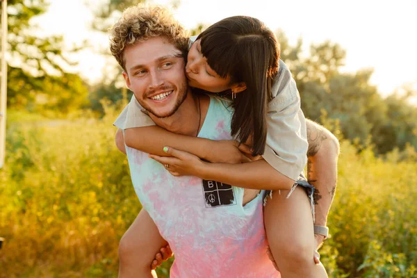 Multiracial Young Couple Kissing Piggybacking Outdoors — Stock Fotó