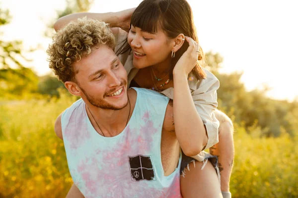 Multiracial Couple Smiling Piggybacking Trailer Outdoors — Zdjęcie stockowe