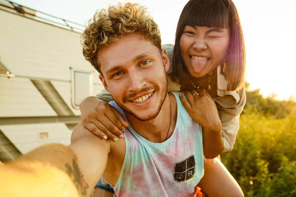 Multiracial Couple Taking Selfie While Piggybacking Trailer Outdoors — Foto de Stock
