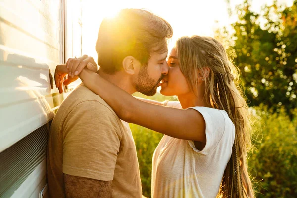 White couple hugging and kissing while standing by trailer outdoors