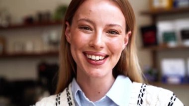 Kahkahalar atan sarışın kadın kafeteryada kameraya bakıyor.