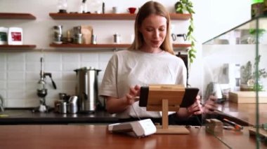 Gülümseyen sarışın kadın kafenin kasasında siparişi yumrukluyor.