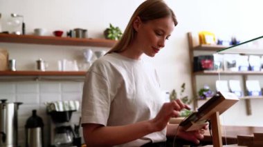 Güzel sarışın kadın kahveci kafedeki kasada siparişi yumrukluyor.