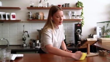 Kahkaha atan sarışın kadın kafedeki masayı siliyor.